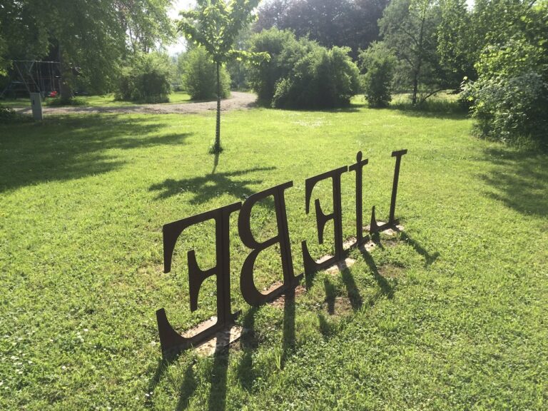 Liebe als Skulptur aus Buchstaben auf grüner Wiese
