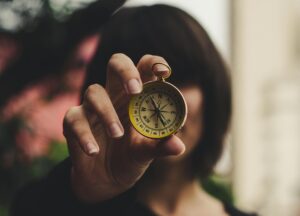 Frau hält Kompass in Kamera